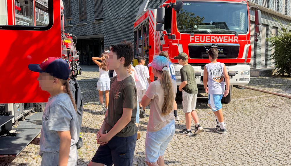 Schülerinnen und Schüler stehen an den Feuerwehrfahrzeugen vor dem Kepler-Gymnasium.