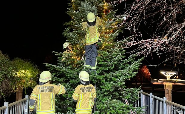 Feuerwehrangehörige dekorieren einen Weihnachtsbaum