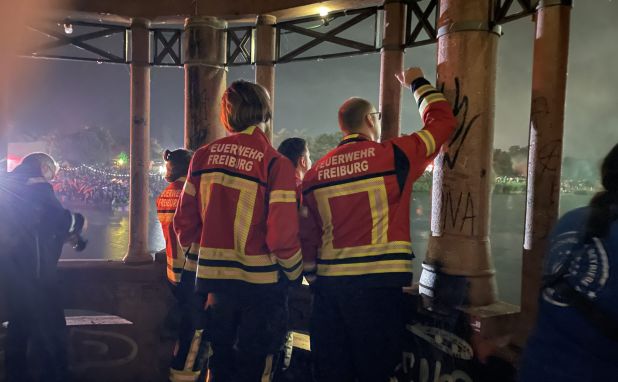Feuerwehrleute blicken in Richtung eines Feuerwerks